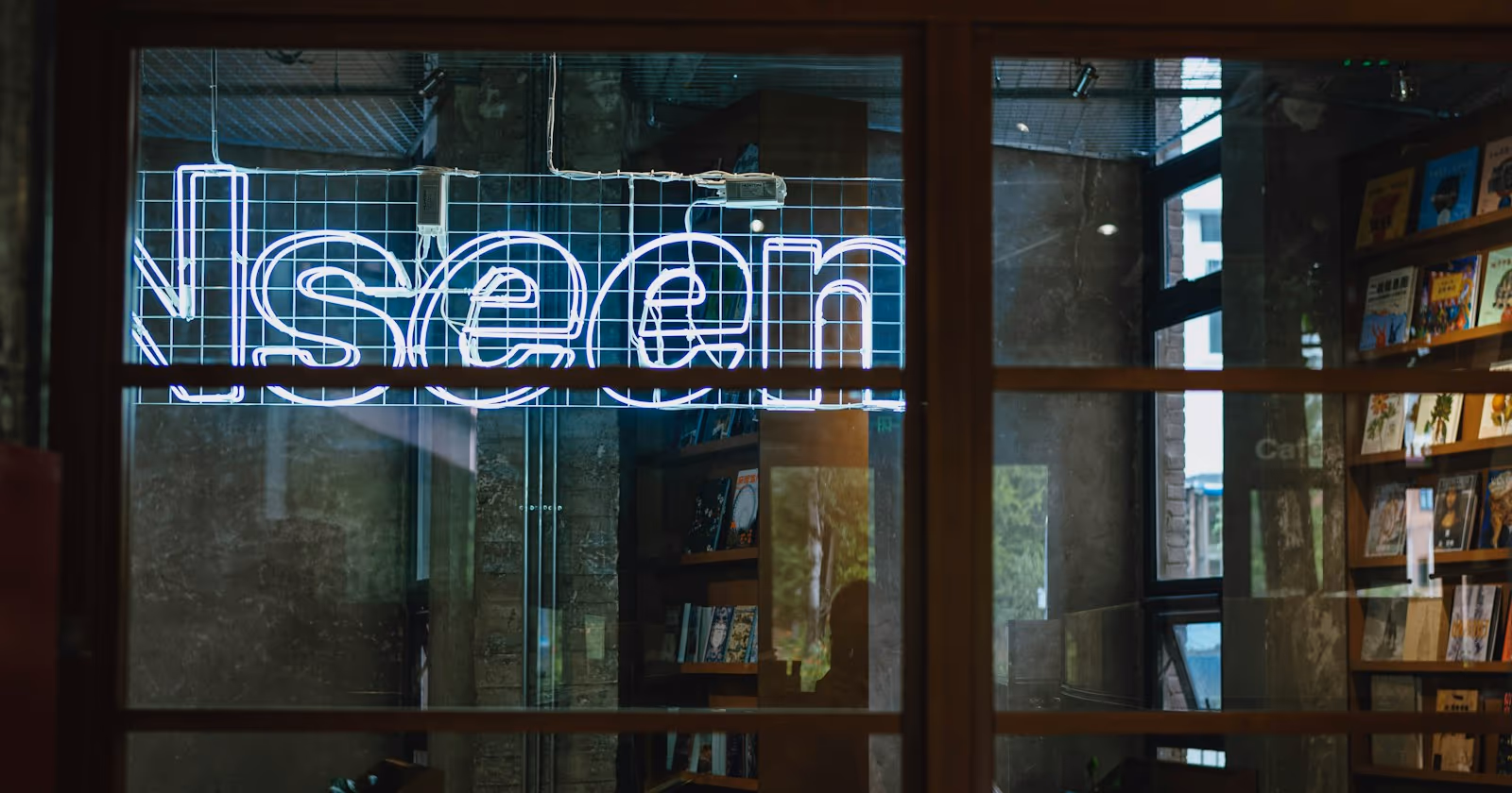 Kitapçı vitrininde "seen" yazan neon tabela, görünür olmayı ve marka bilinirliğini simgeleyen kapak görseli